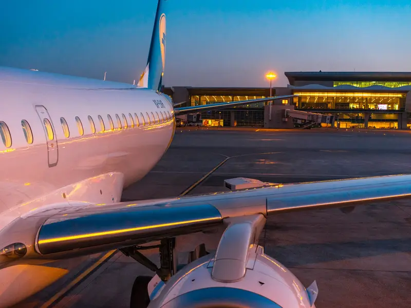 Avion na aerodromu u sumrak, s osvijetljenim terminalom